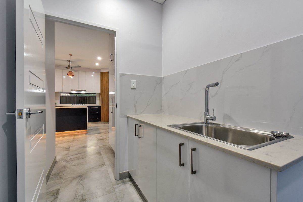 A kitchen with a sink and cabinets and a door leading to a kitchen.
