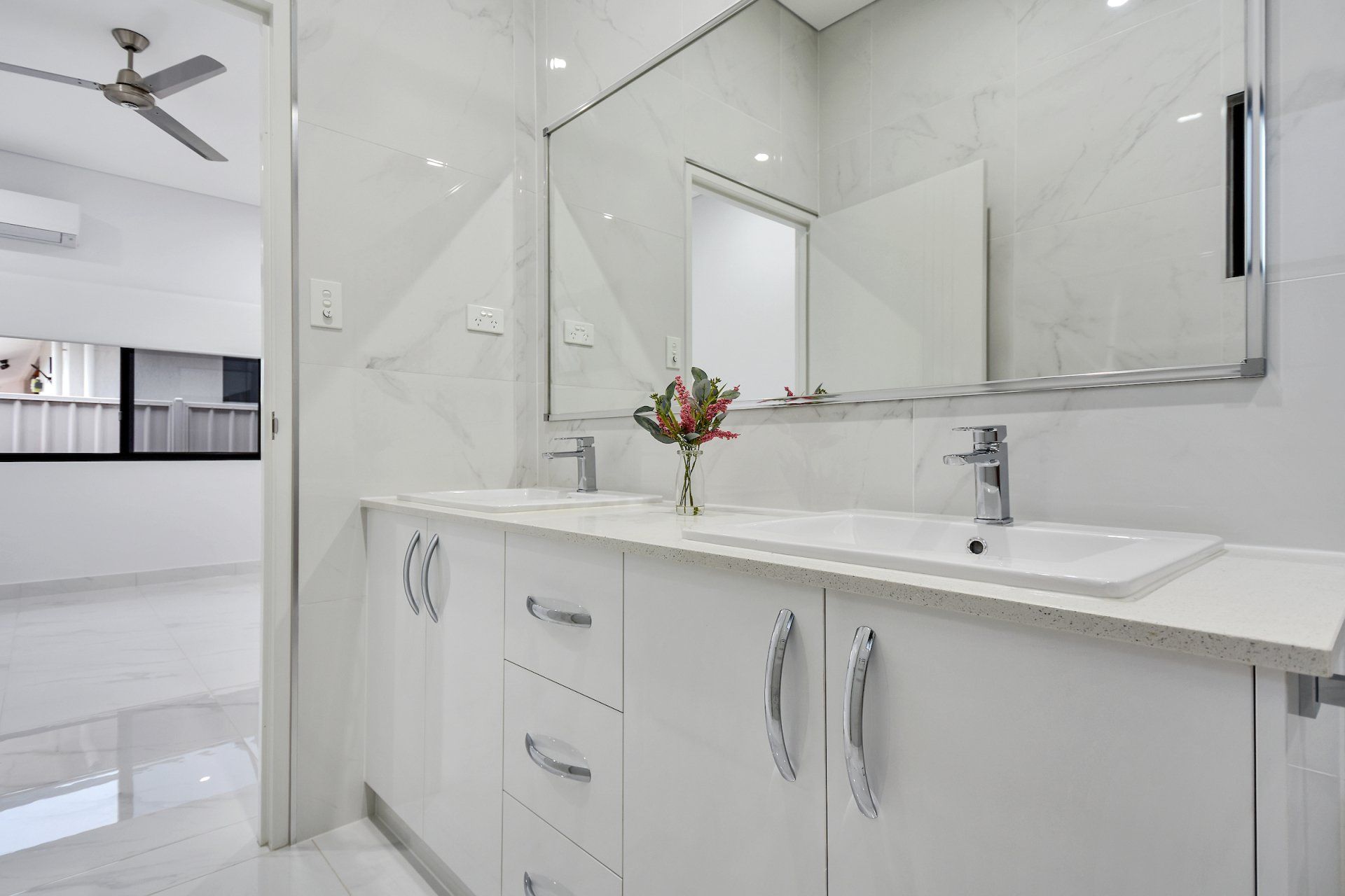 A bathroom with two sinks , a mirror and a ceiling fan.