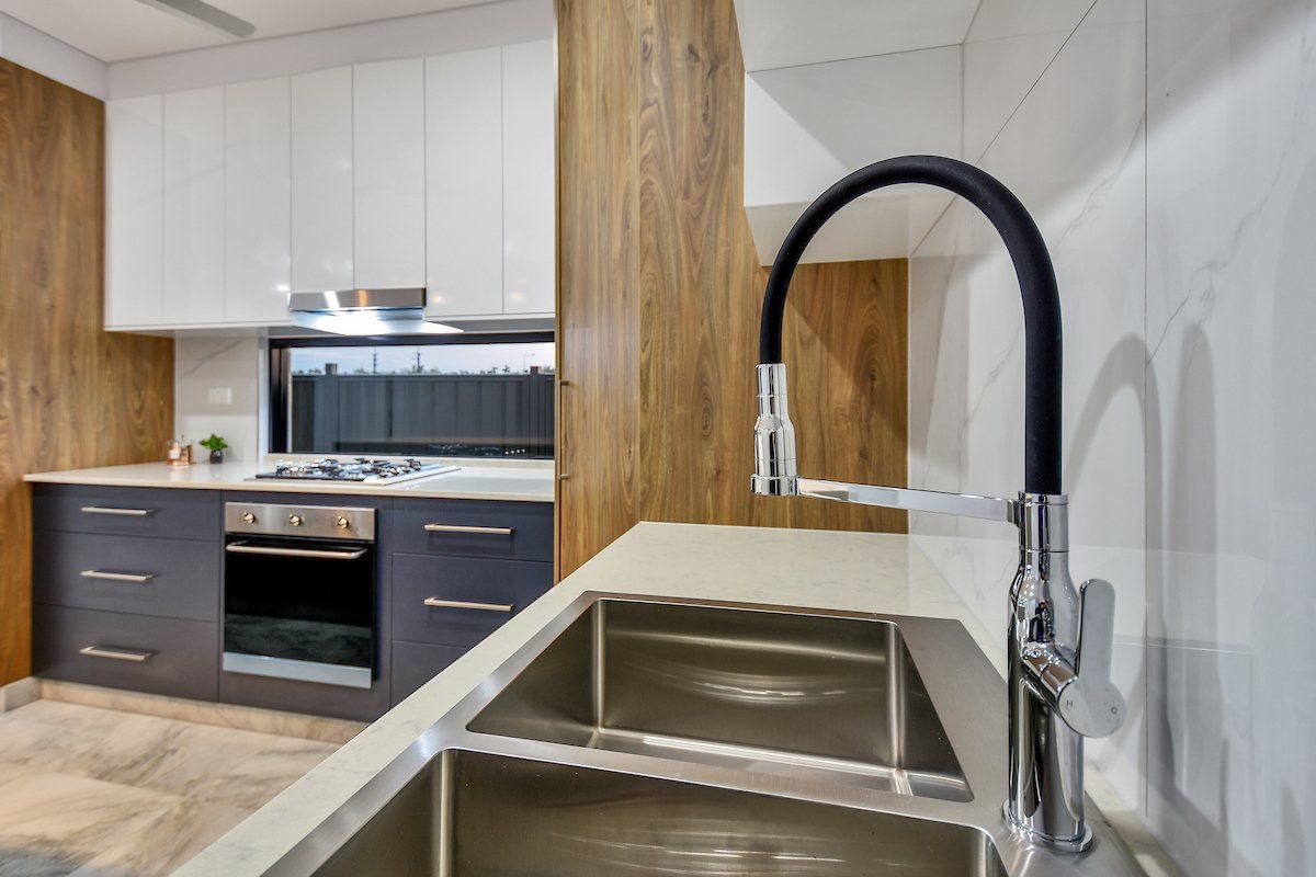 A kitchen with a stainless steel sink and a black faucet