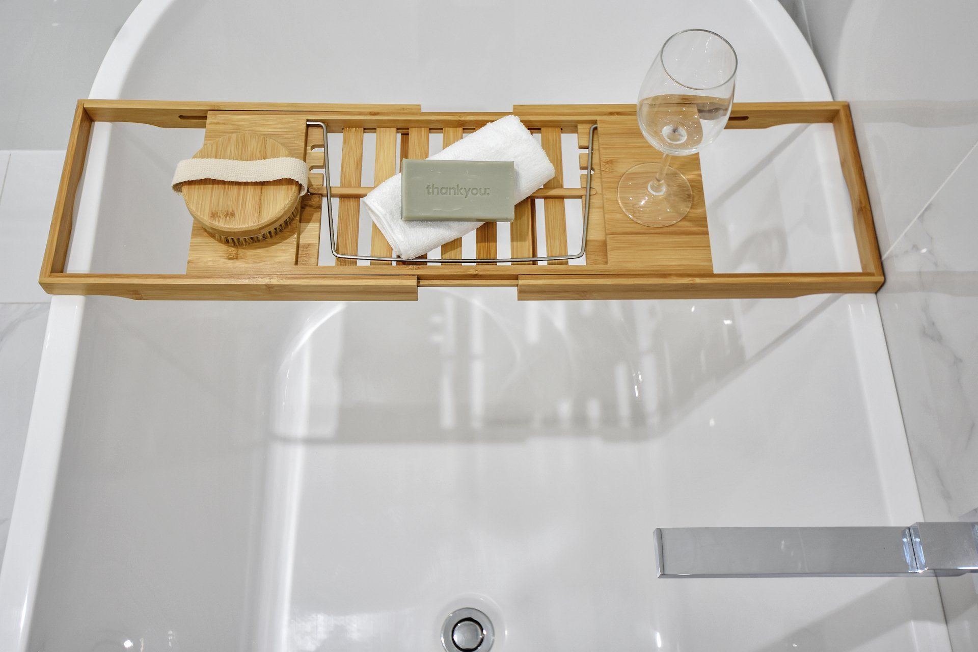 A bathtub with a wooden tray on top of it.