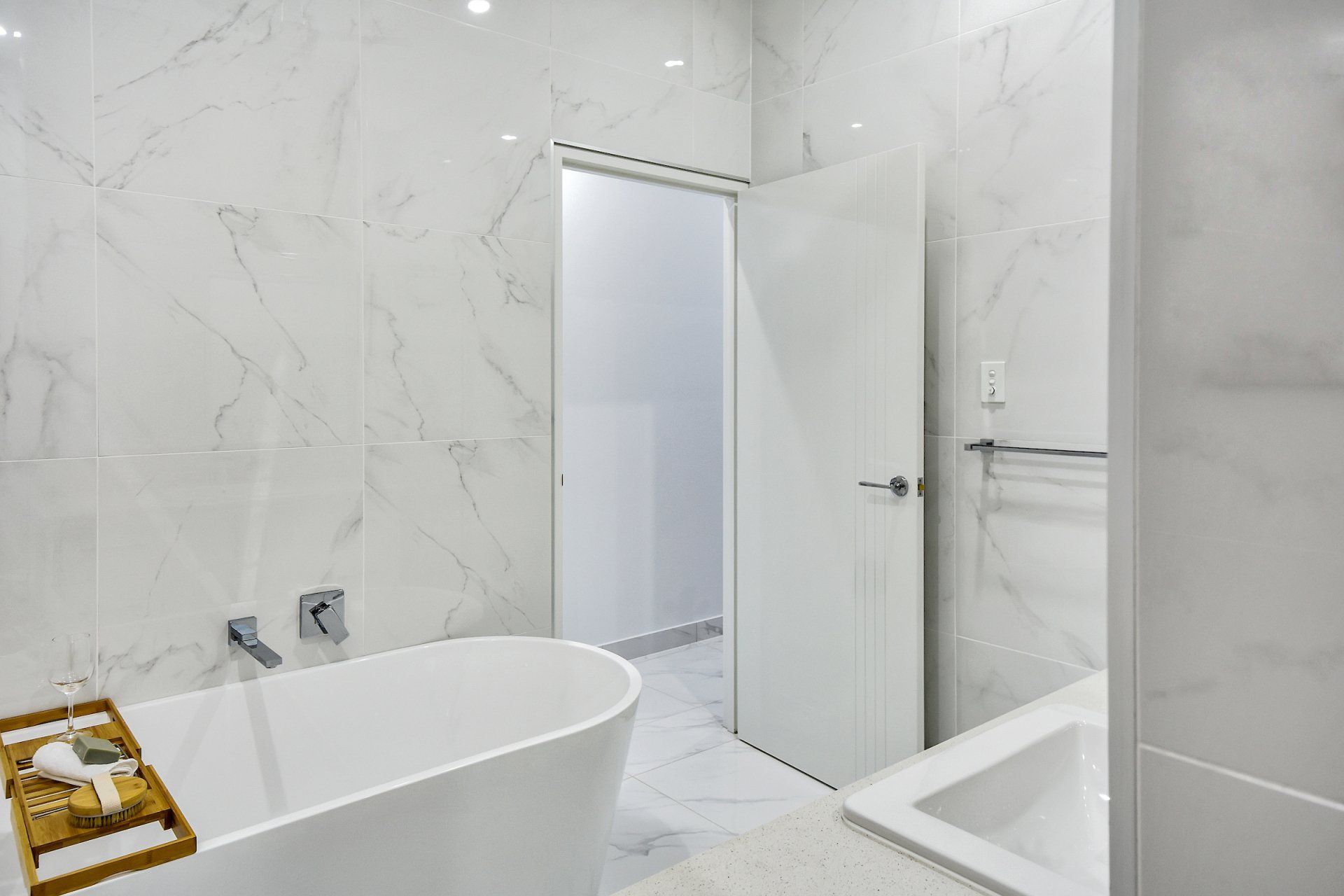 A bathroom with a bathtub , sink , and door.