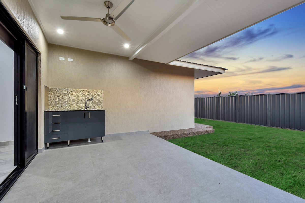 A patio with a sink and a ceiling fan in the backyard of a house.
