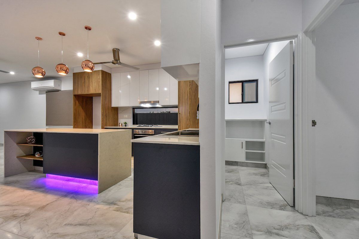 A kitchen with a large island and purple lights on the floor.