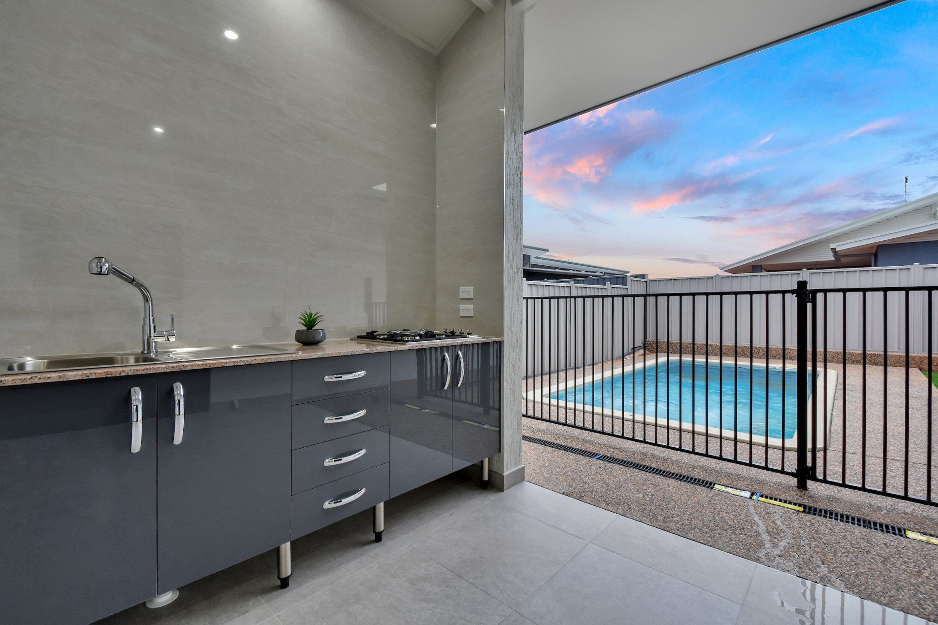 A kitchen with a sink and a pool in the background.