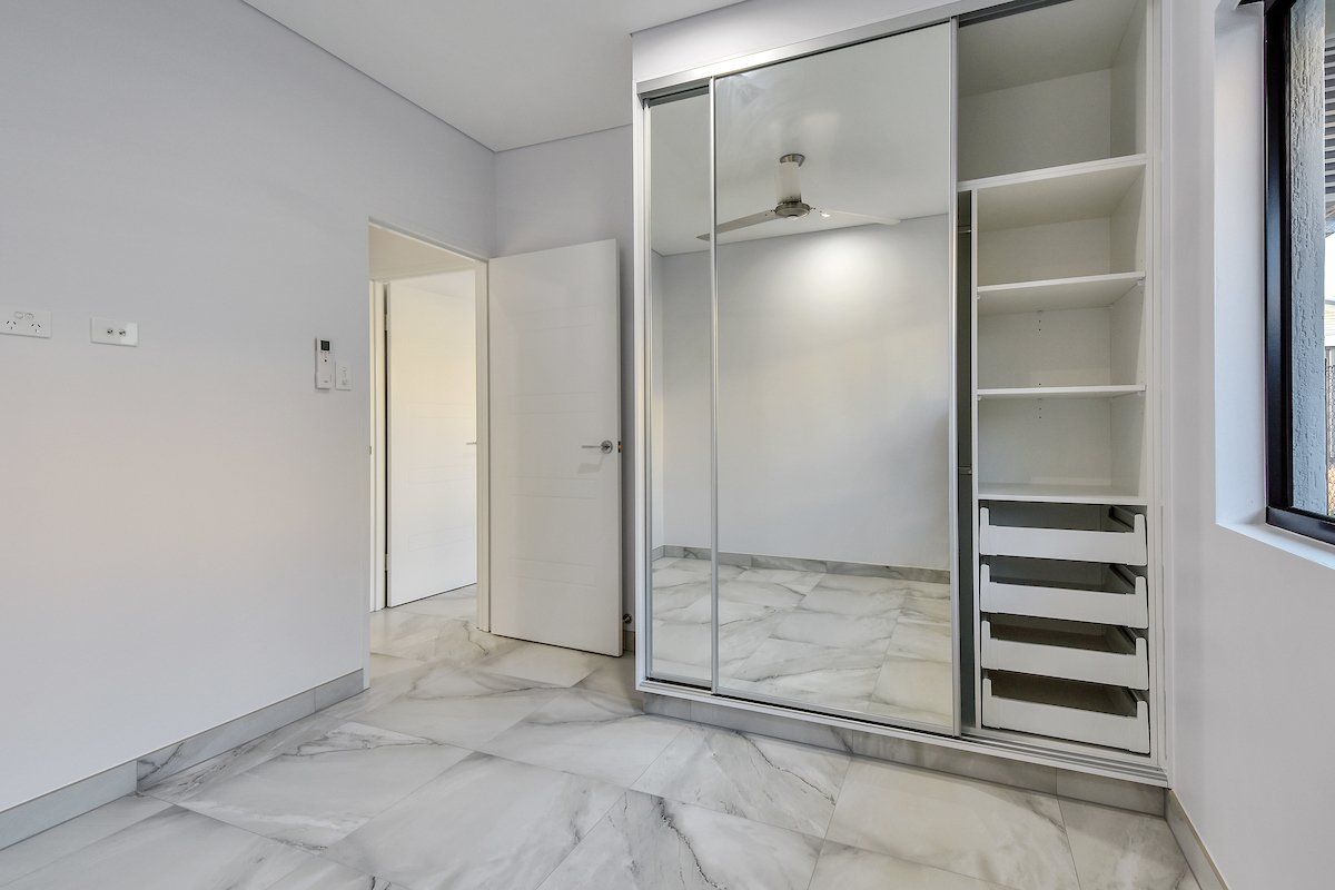 An empty bedroom with a large mirrored wardrobe and a window.