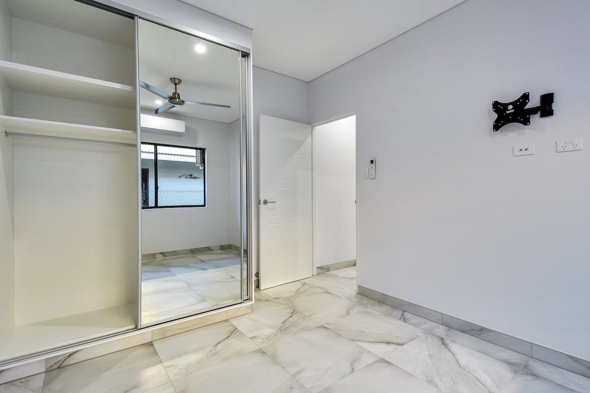 A bedroom with a large mirror on the wall and a ceiling fan.