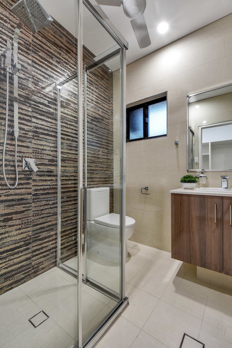 A bathroom with a walk in shower , toilet , sink and mirror.