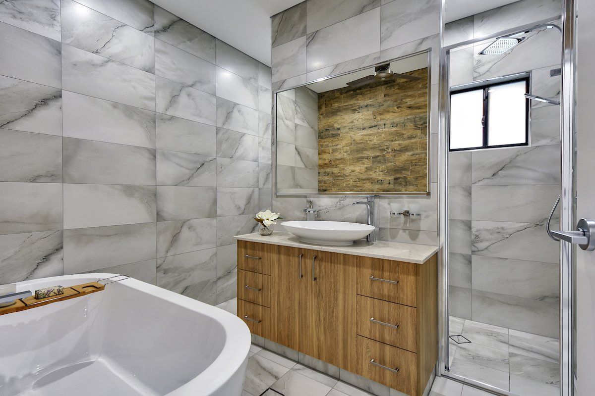 A bathroom with a tub , sink , mirror and shower.