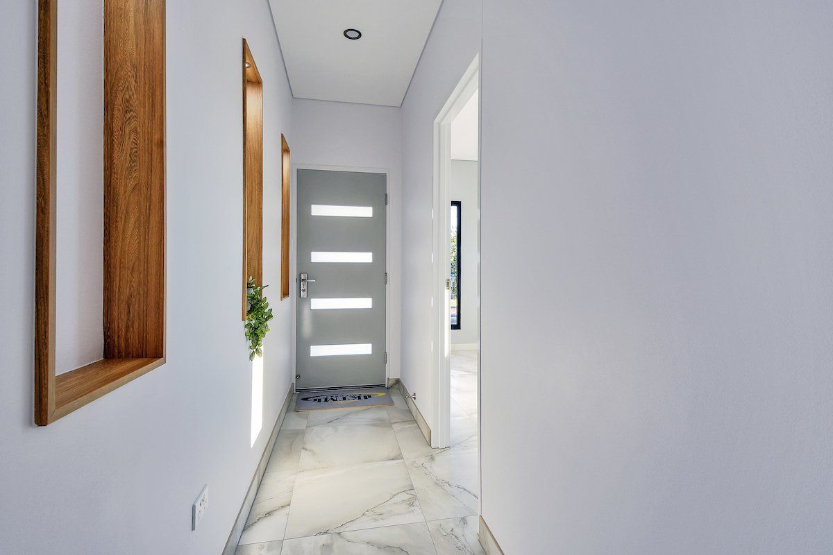 A hallway in a house with a door and a mirror.