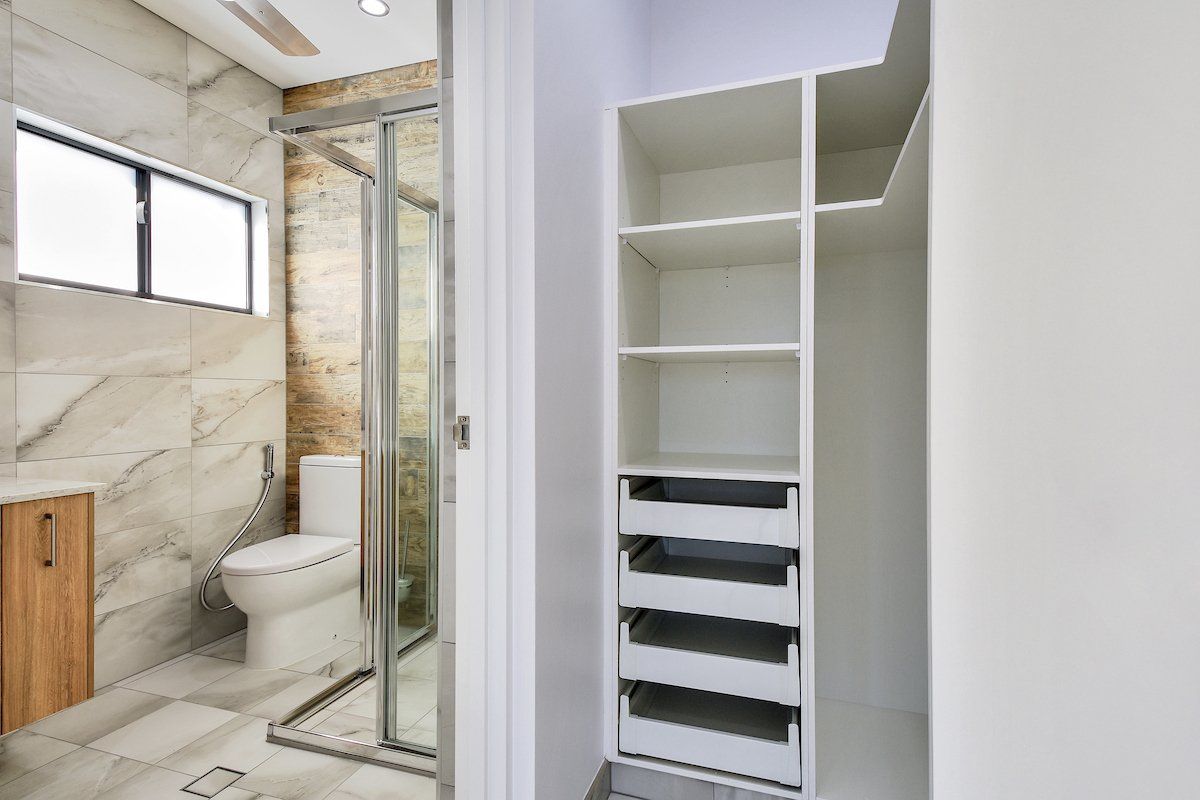 A bathroom with a toilet and a walk in closet.