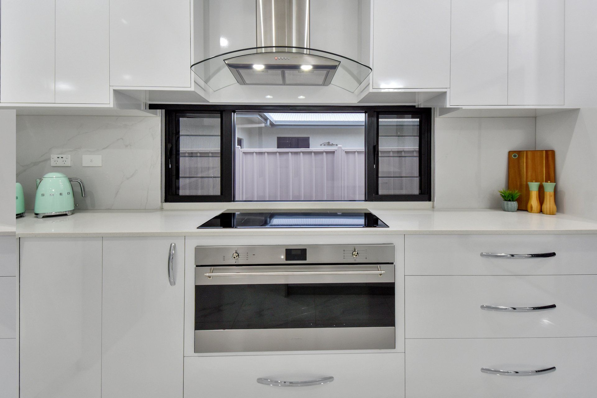 A kitchen with white cabinets , stainless steel appliances , a stove and a window.