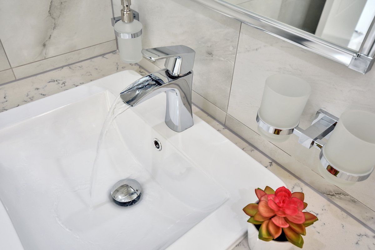 A bathroom sink with a faucet and a flower on the counter.