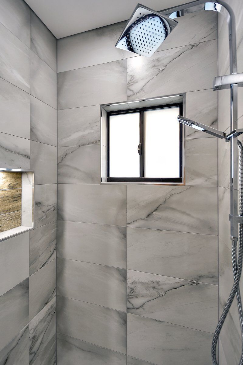 A shower with a window and a shower head.