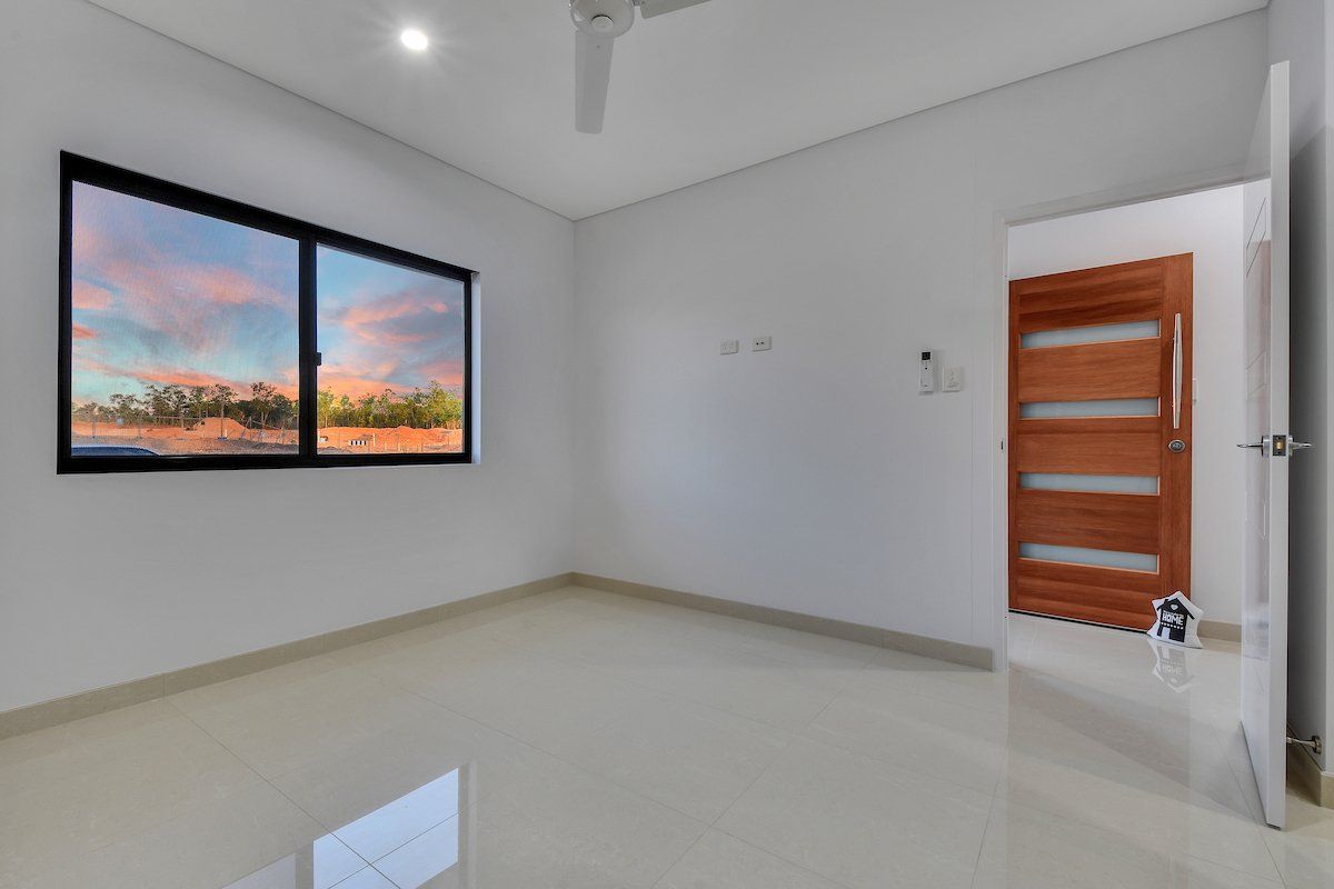 An empty room with two windows and a ceiling fan.