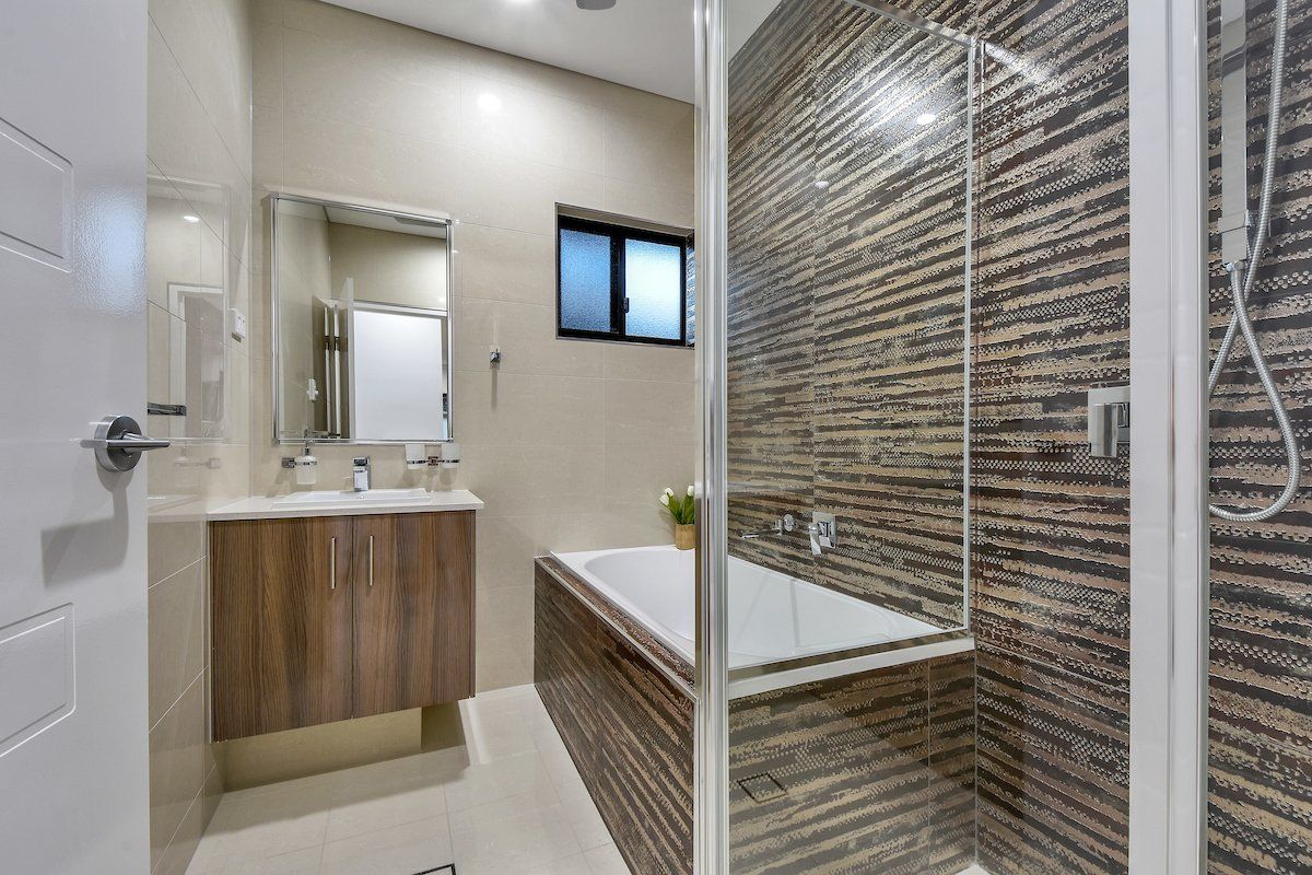 A bathroom with a tub , sink , shower and mirror.