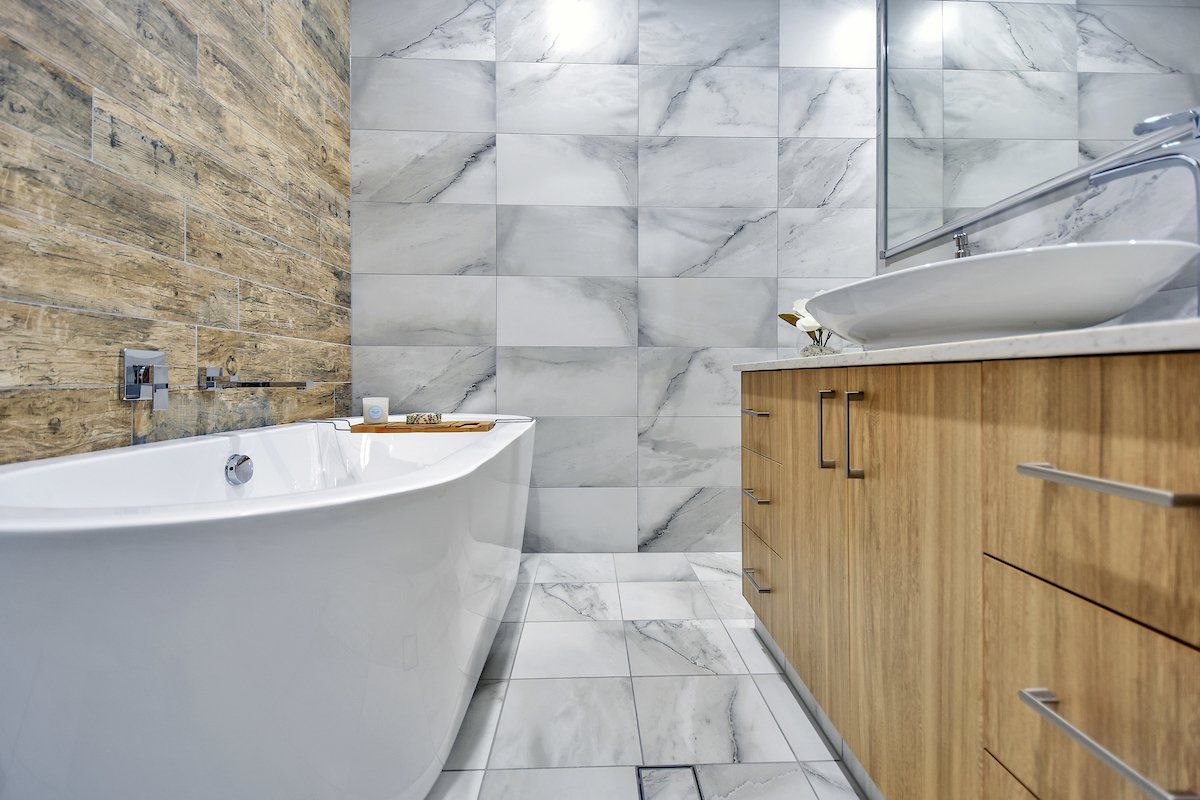 A bathroom with a bathtub , sink and mirror.