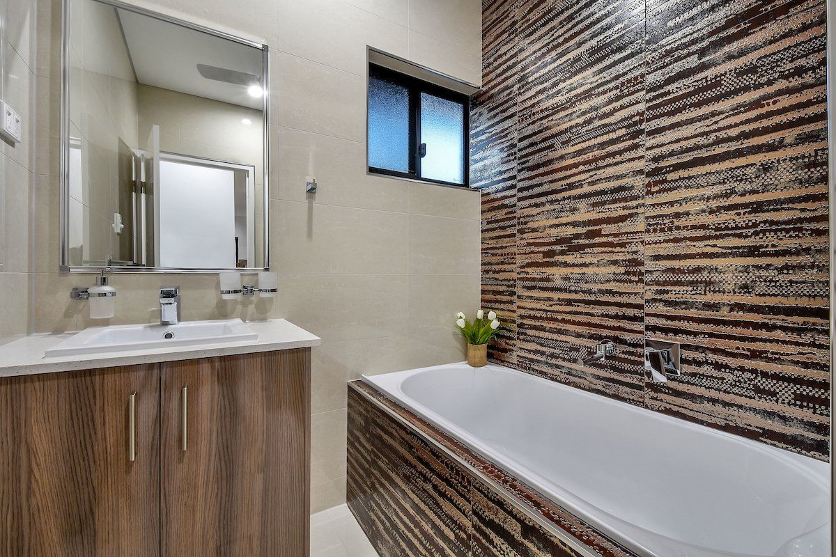 A bathroom with a tub , sink , mirror and window.