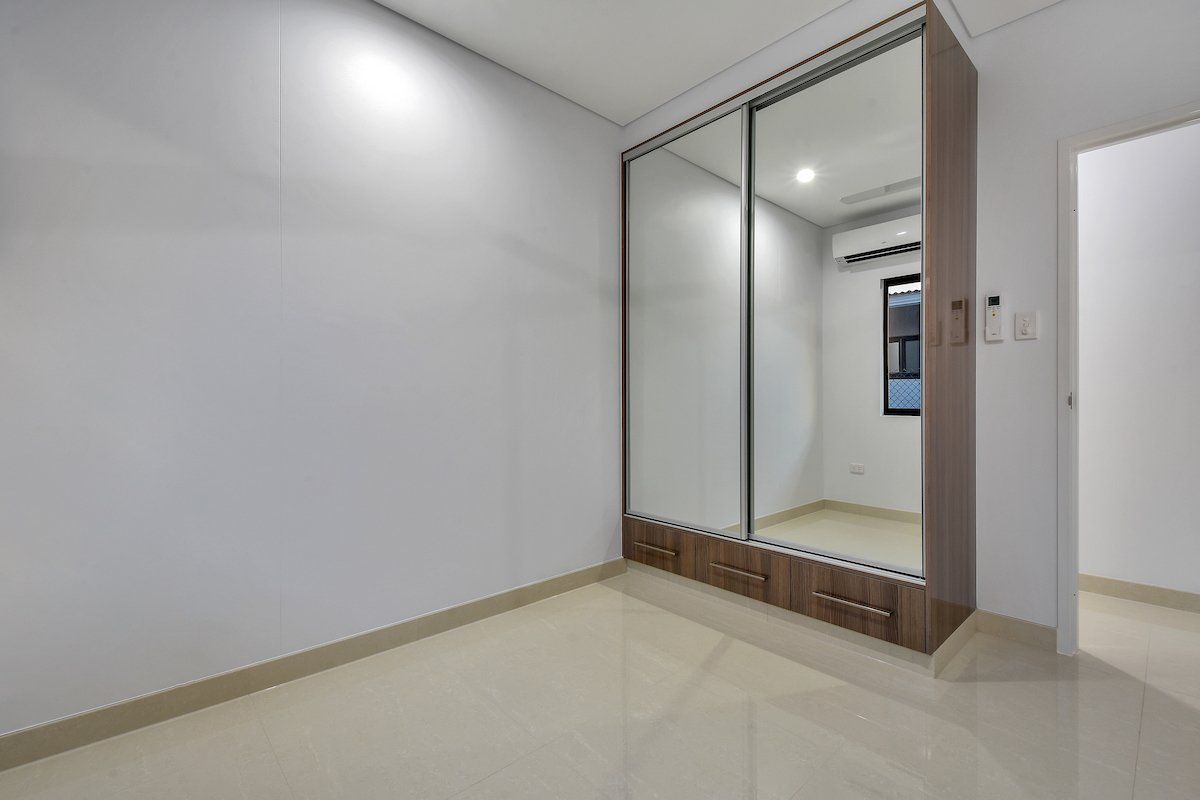 An empty bedroom with a large mirrored wardrobe.