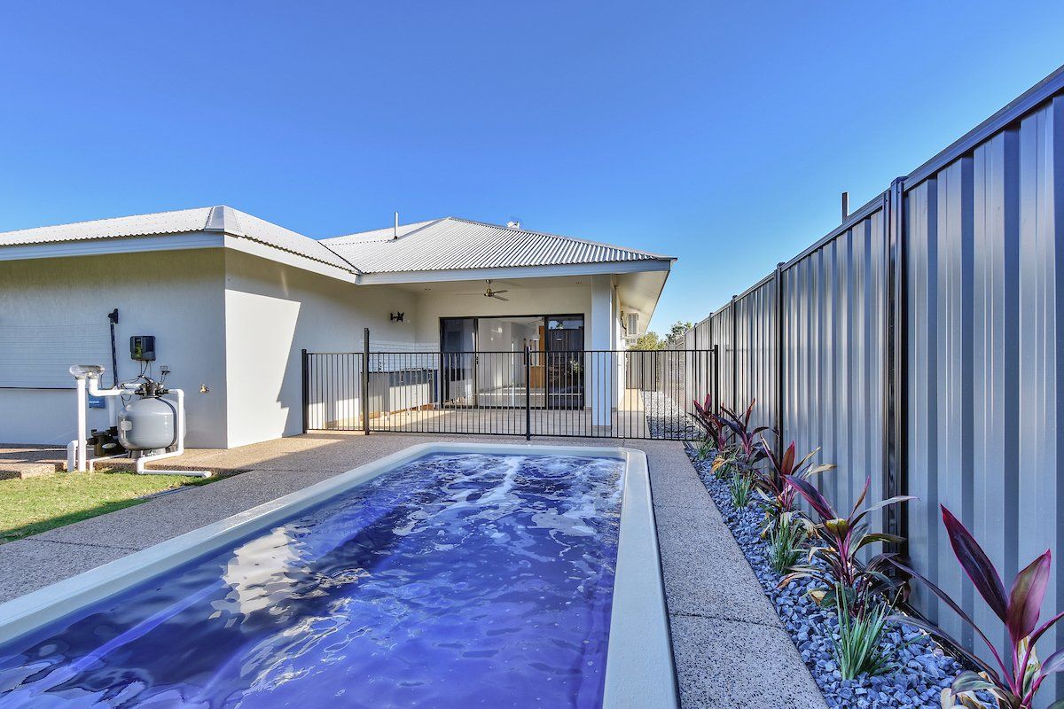 A large swimming pool is in the backyard of a house.