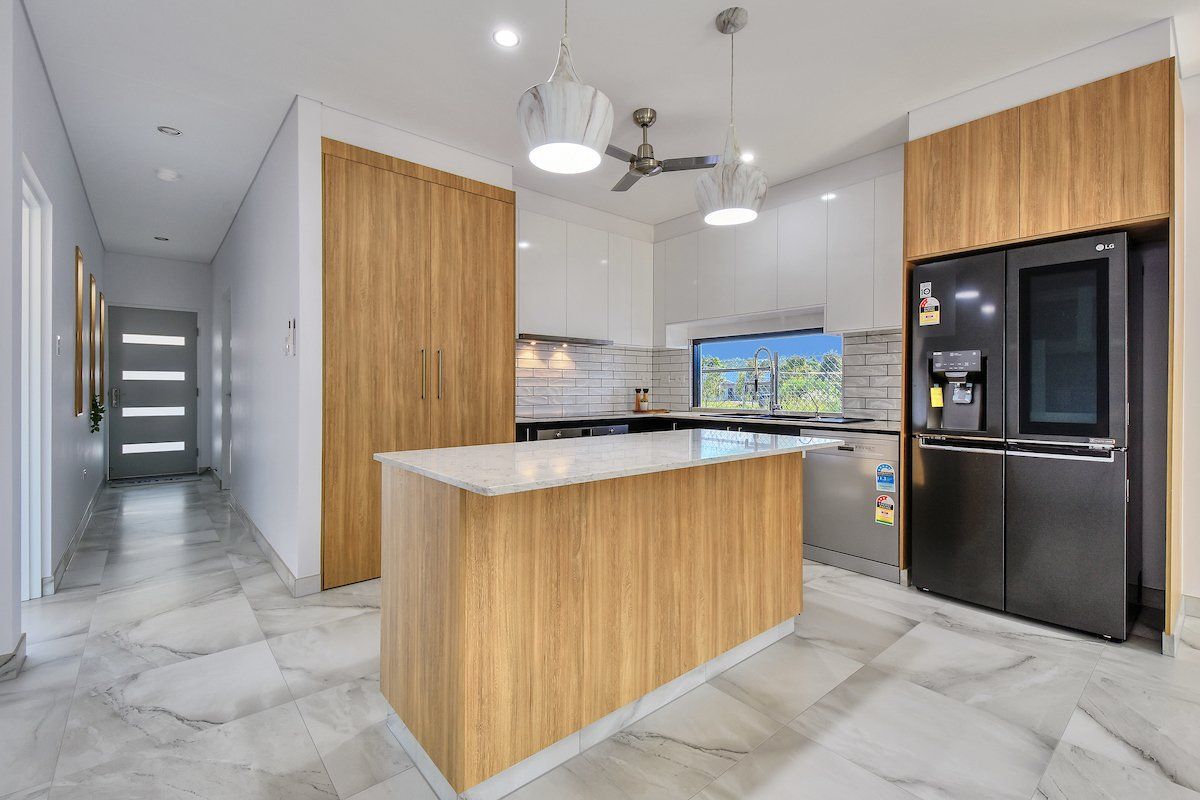 A kitchen with a large island and a black refrigerator.