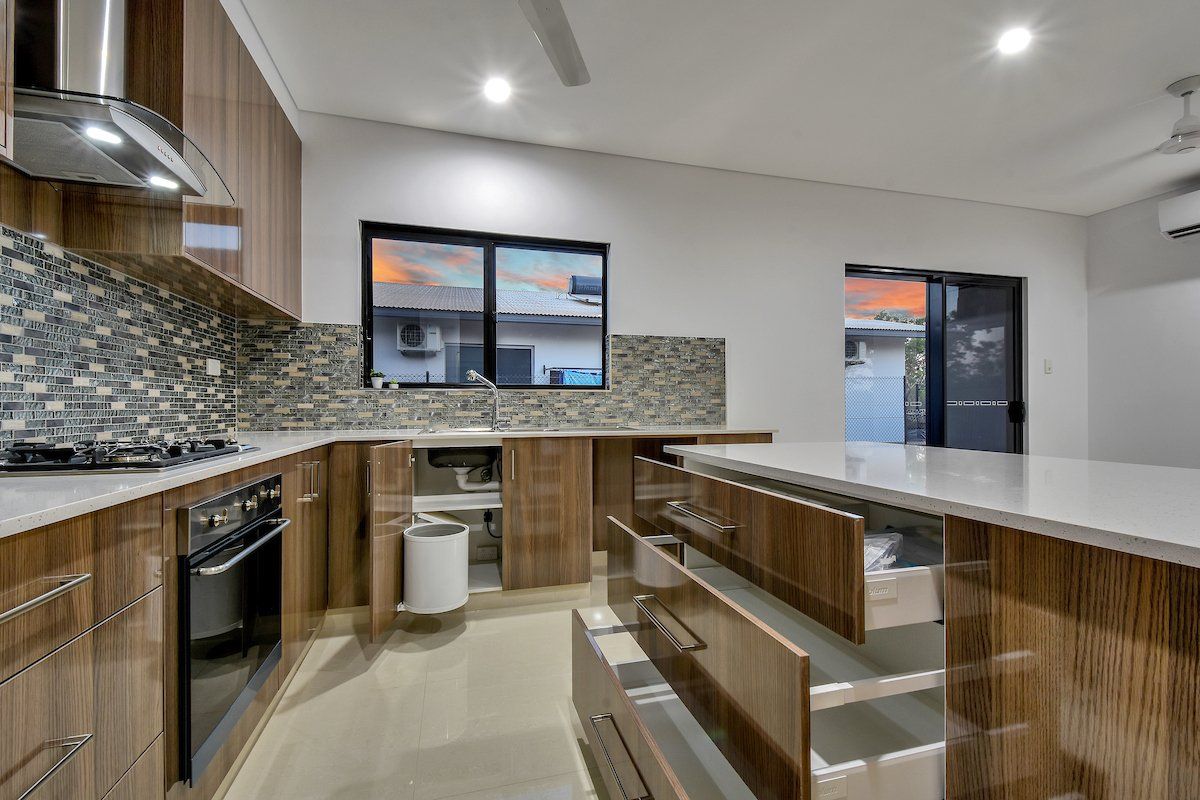 A kitchen with wooden cabinets , stainless steel appliances , and white counter tops.