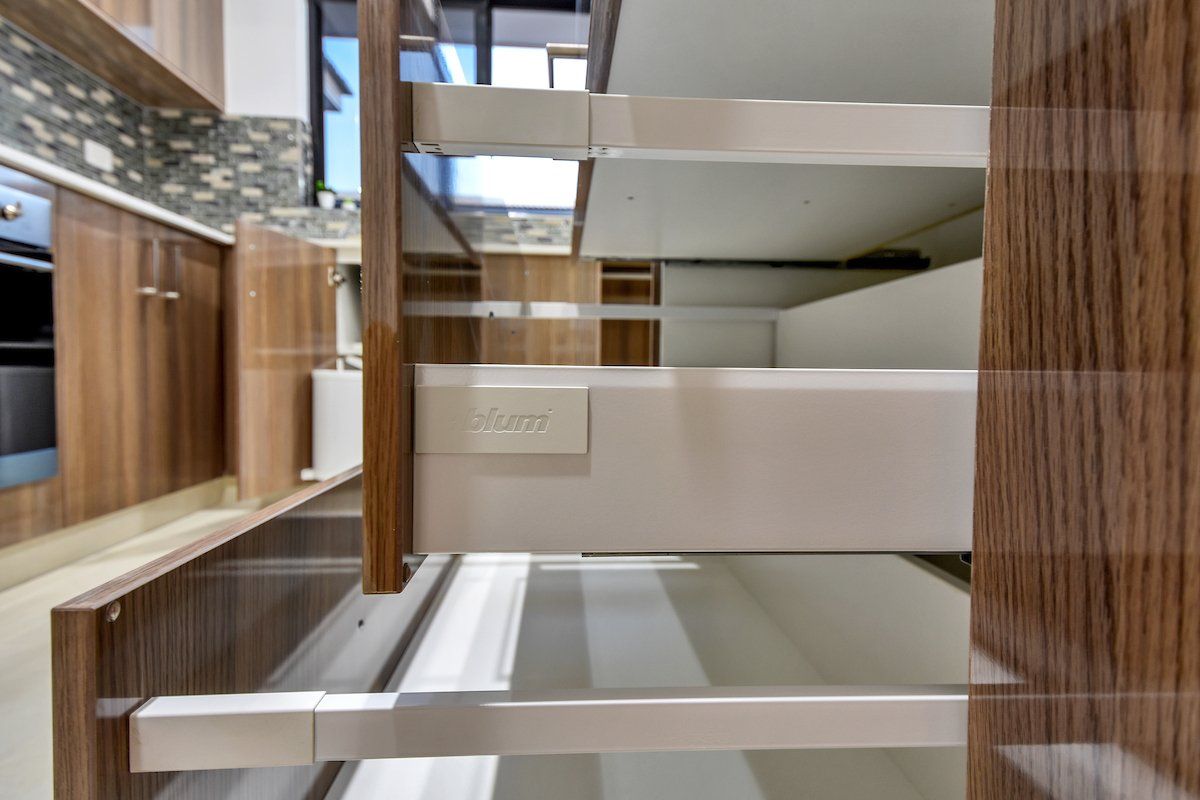 A kitchen with wooden cabinets and white drawers.