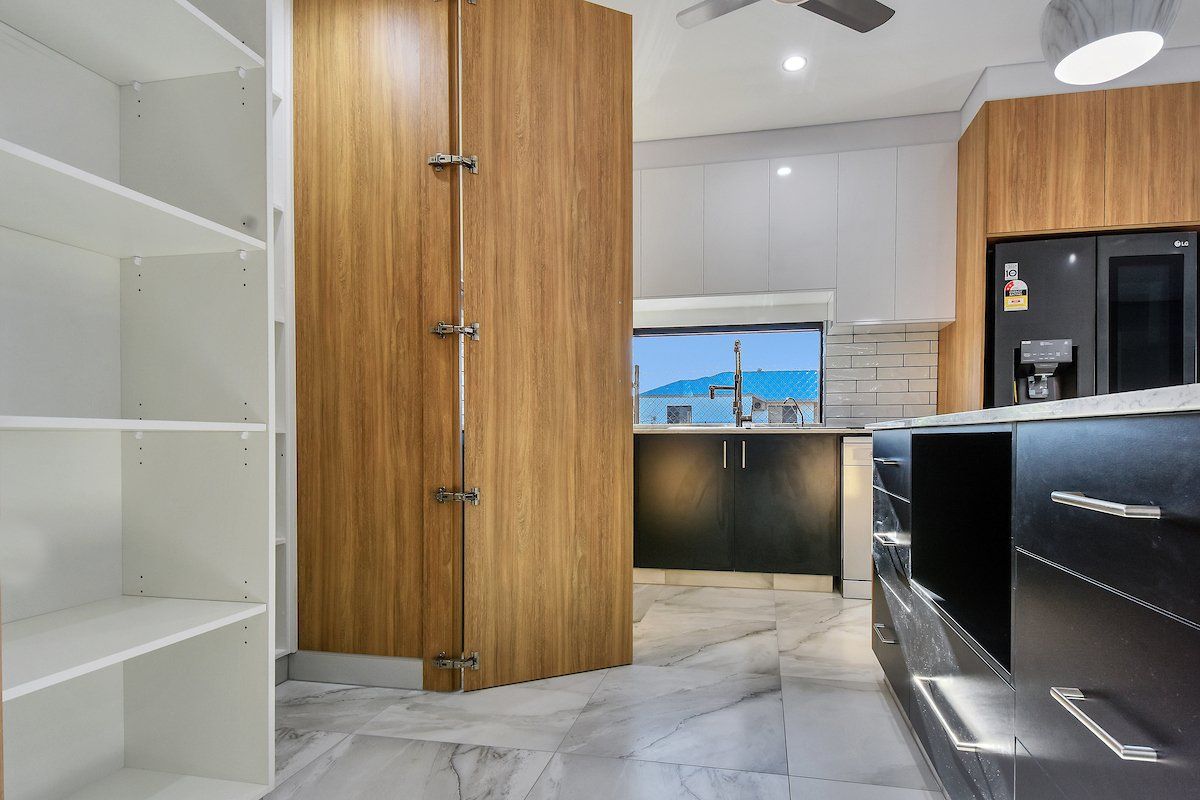 A kitchen with black cabinets and white shelves and a ceiling fan.