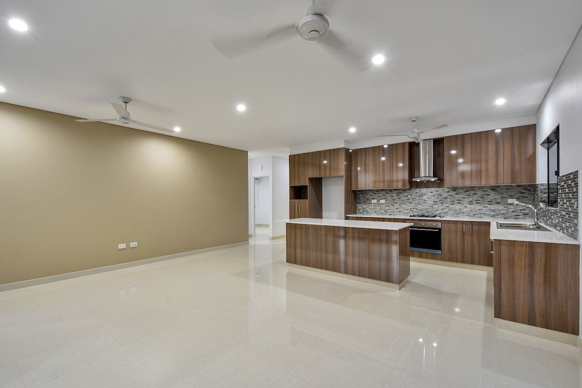 An empty kitchen with wooden cabinets and a ceiling fan.
