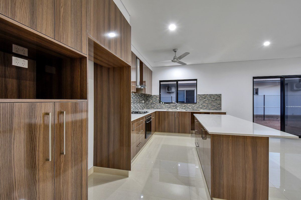 A kitchen with wooden cabinets and white counter tops.