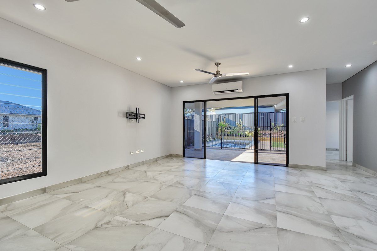 An empty living room with marble floors and a ceiling fan.