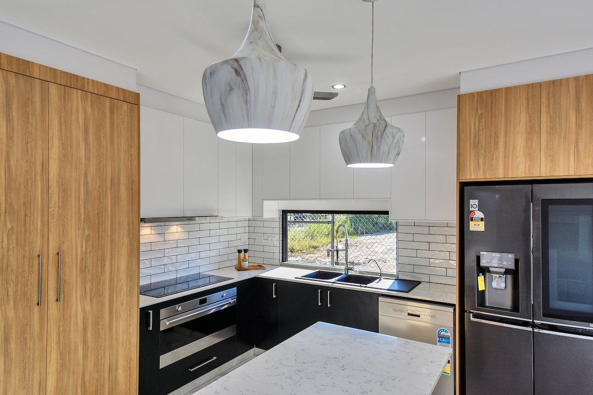A kitchen with a black refrigerator and a white counter top.