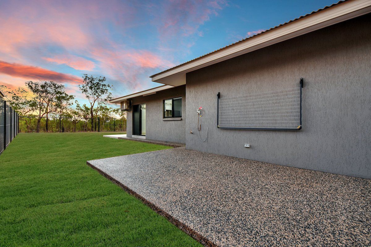 A house with a lawn in front of it and a gravel driveway.