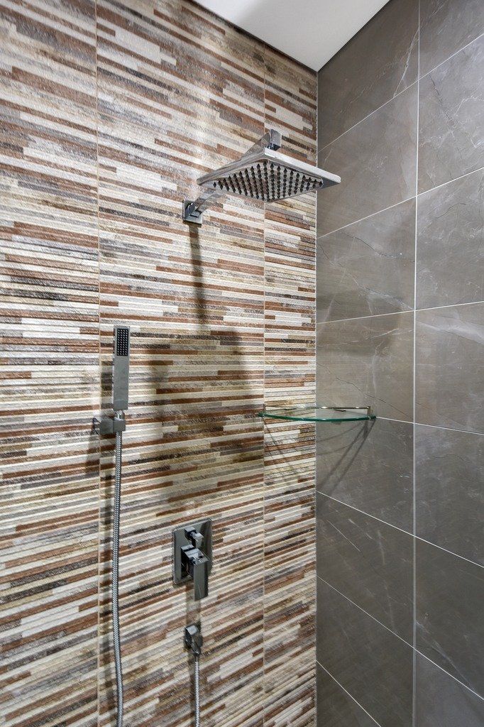 A shower with a tiled wall and a shower head.