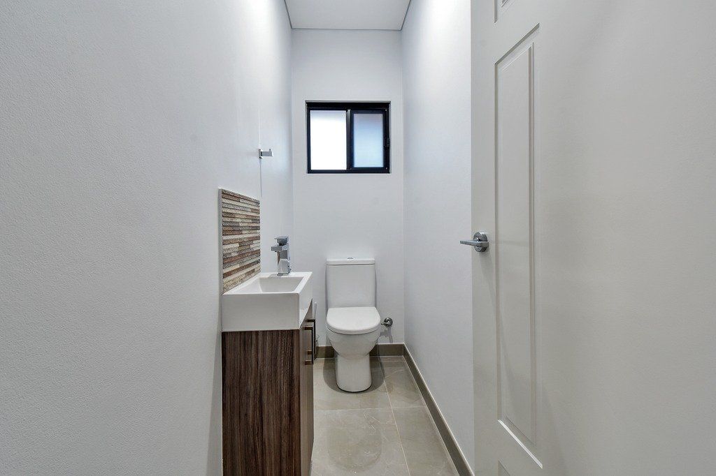 A bathroom with a toilet , sink and window.