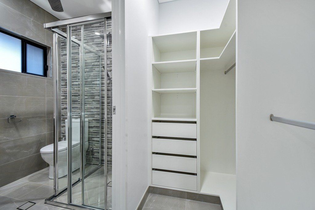 A bathroom with a toilet , shower and closet.