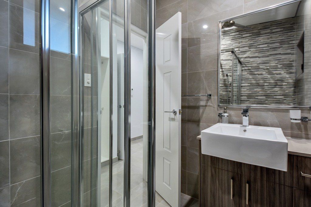 A bathroom with a sink , mirror and shower stall.