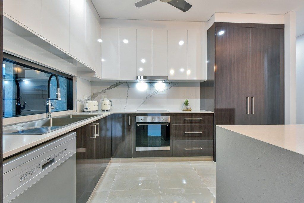 A kitchen with a sink , stove , dishwasher and ceiling fan.