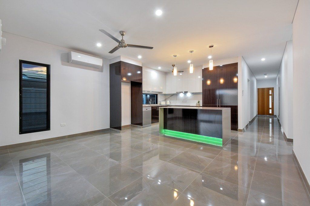 An empty living room with a ceiling fan and a kitchen.