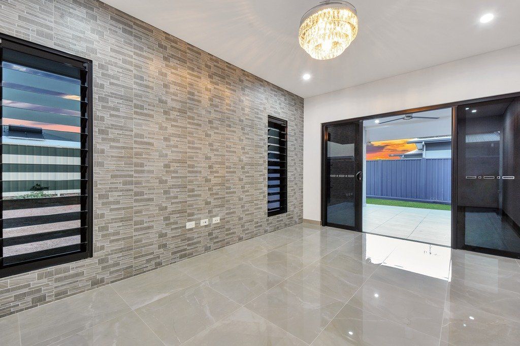 A large empty room with a brick wall and a chandelier.