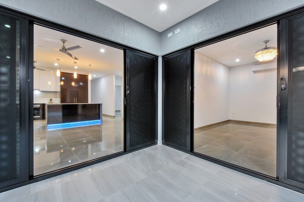 A room with a lot of windows and a kitchen in the background.