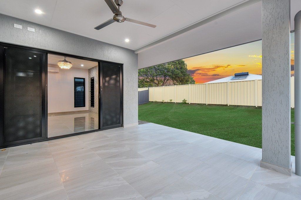 An empty patio with a ceiling fan and sliding glass doors leading to a backyard.