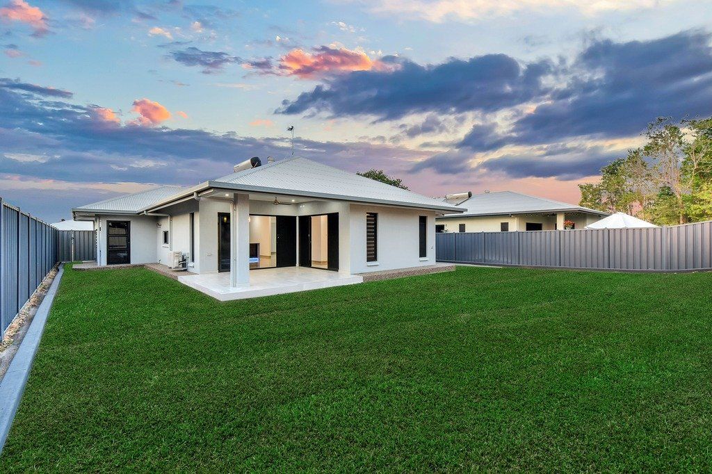 A house with a large lawn in front of it and a fence.