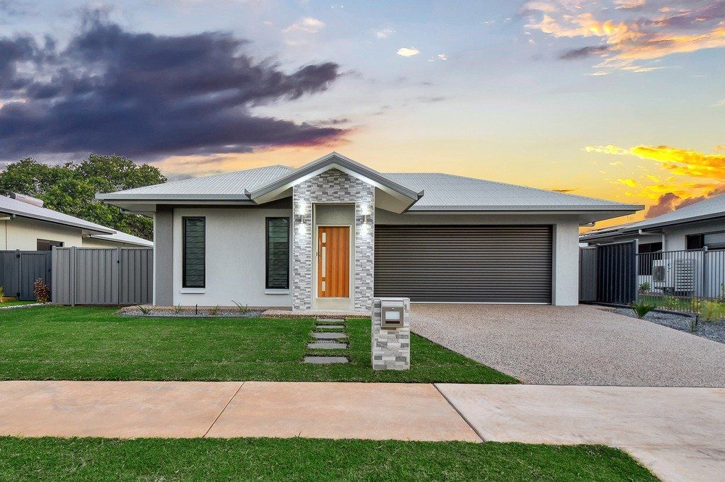 A white house with a large driveway and a fence in front of it.