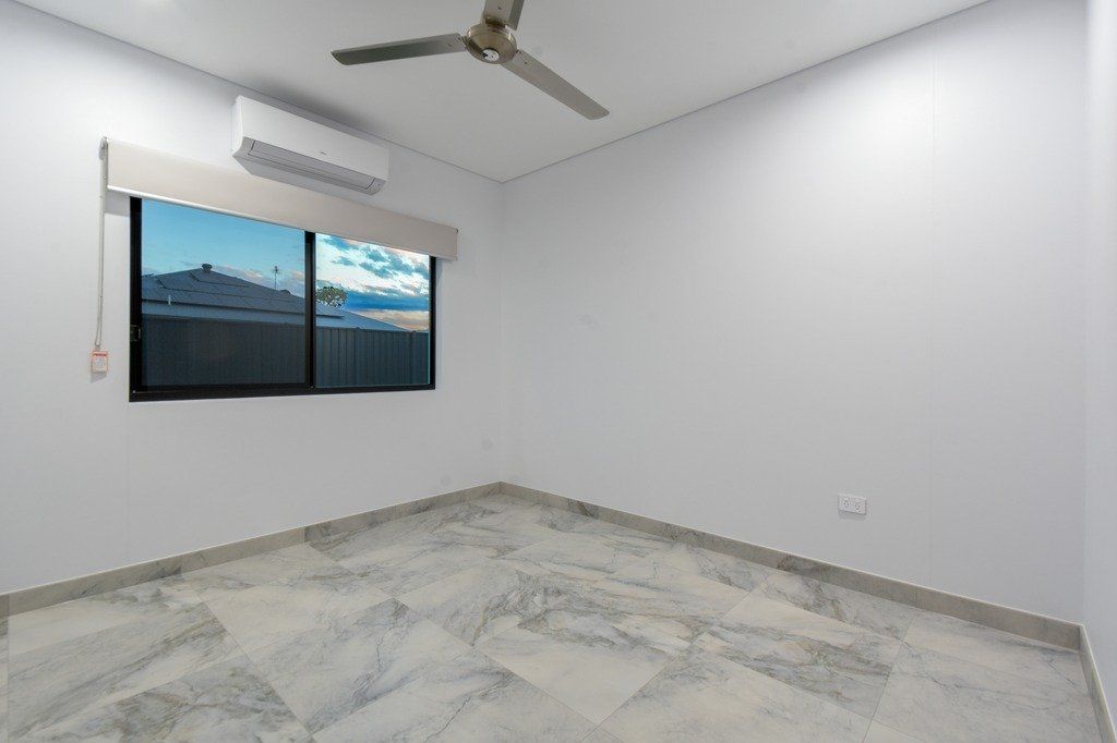 An empty bedroom with a ceiling fan and two windows.