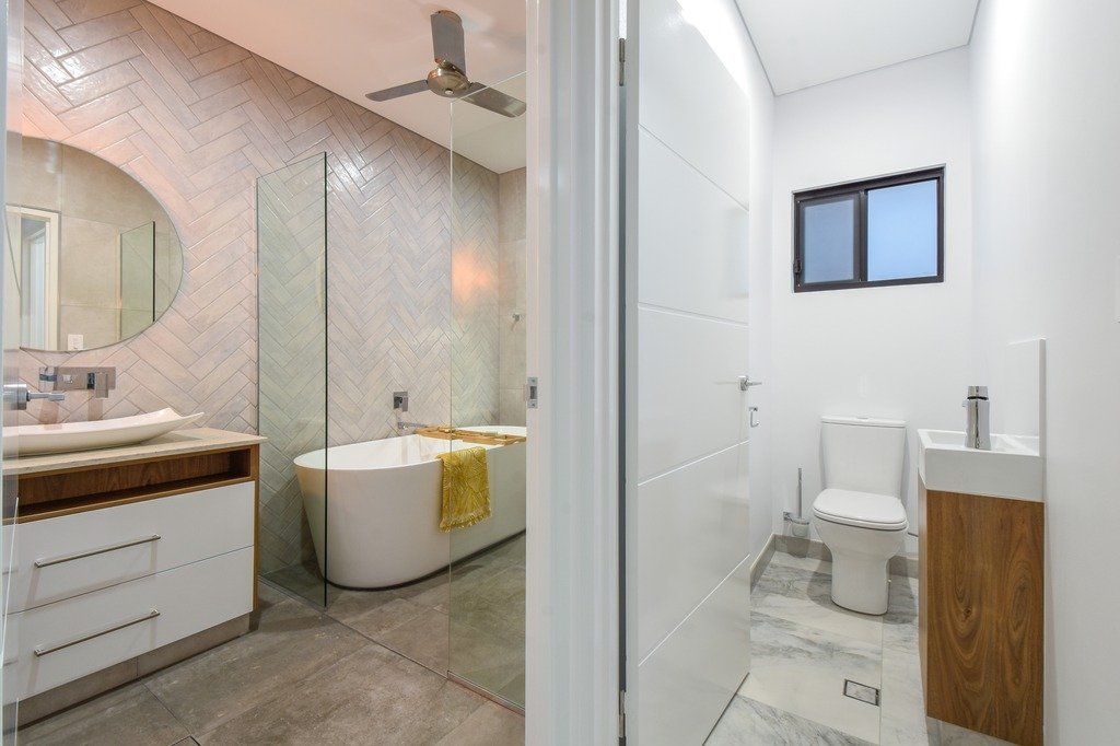 A bathroom with a tub , toilet , sink and mirror.