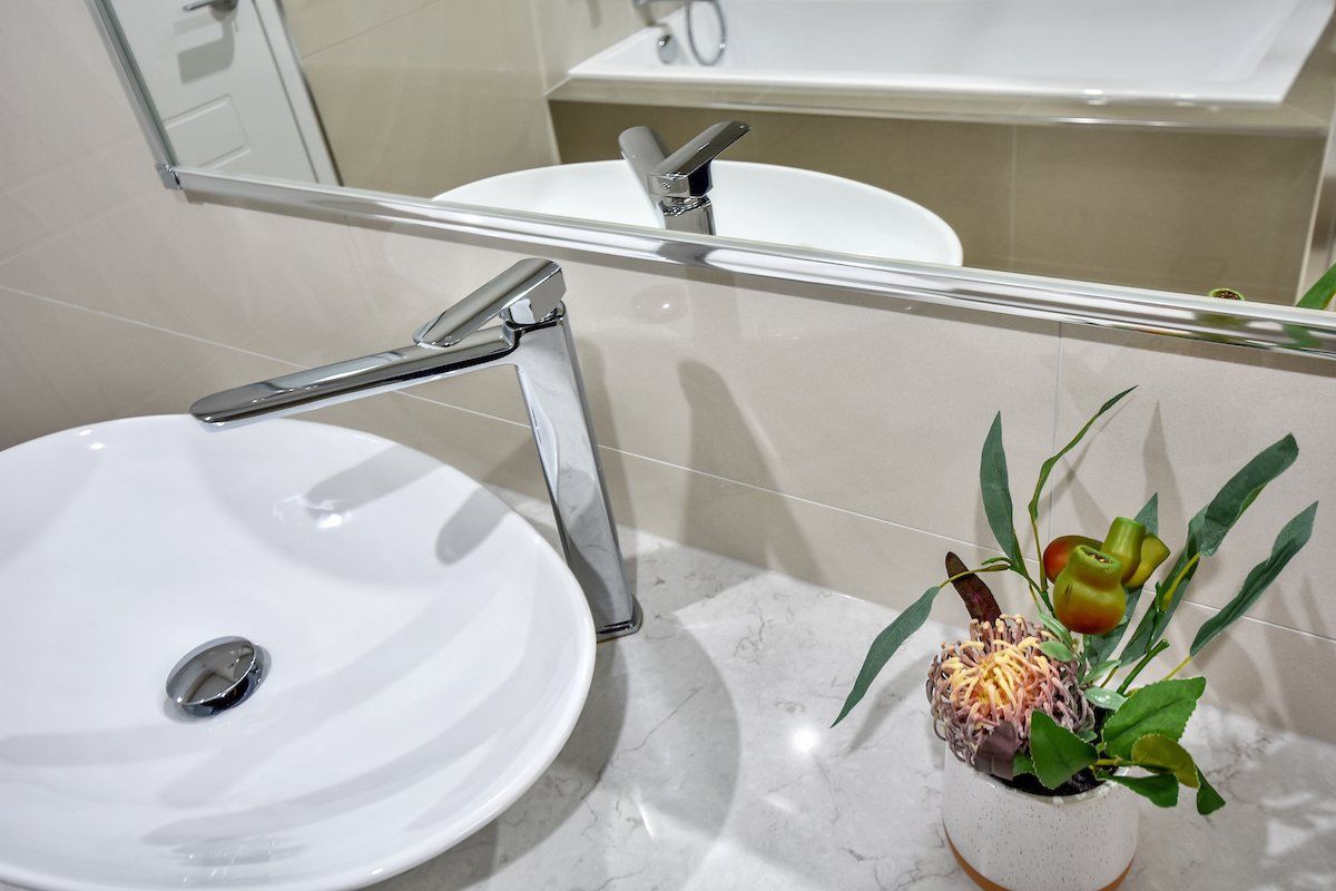 A bathroom sink with a vase of flowers next to it