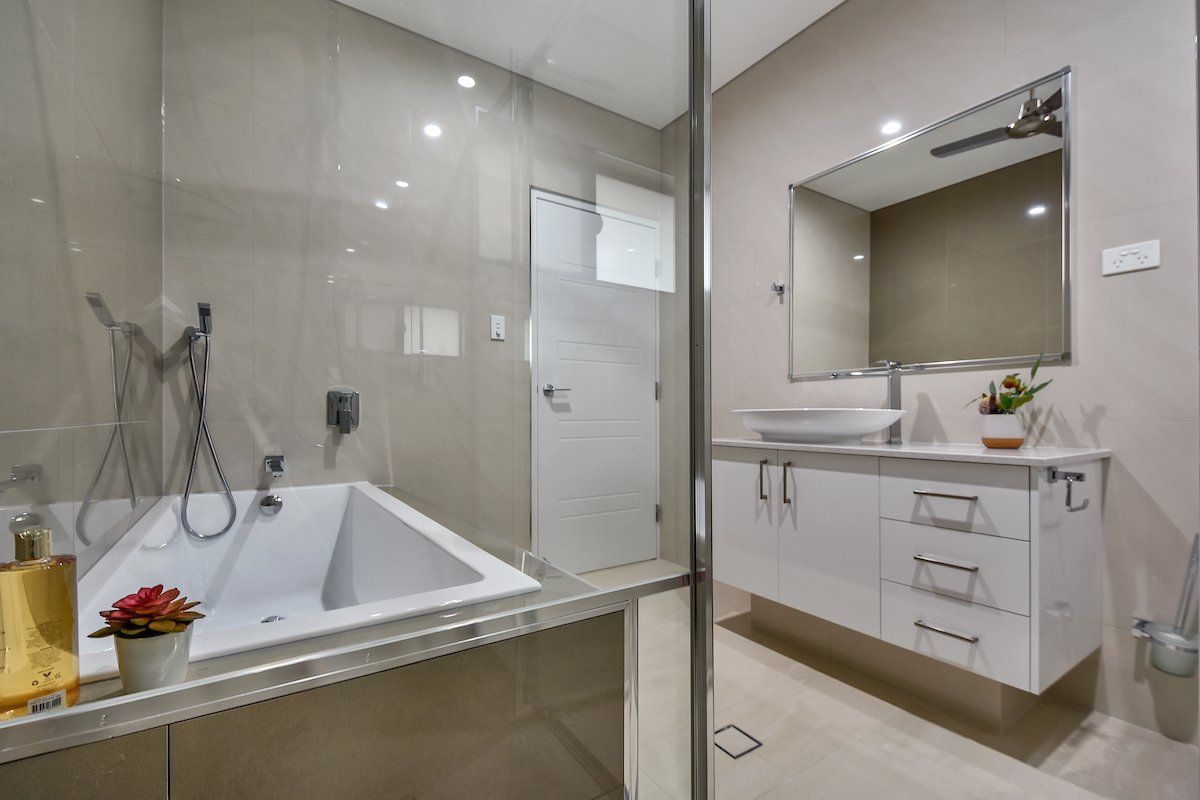A bathroom with a bathtub , sink , mirror and shower.