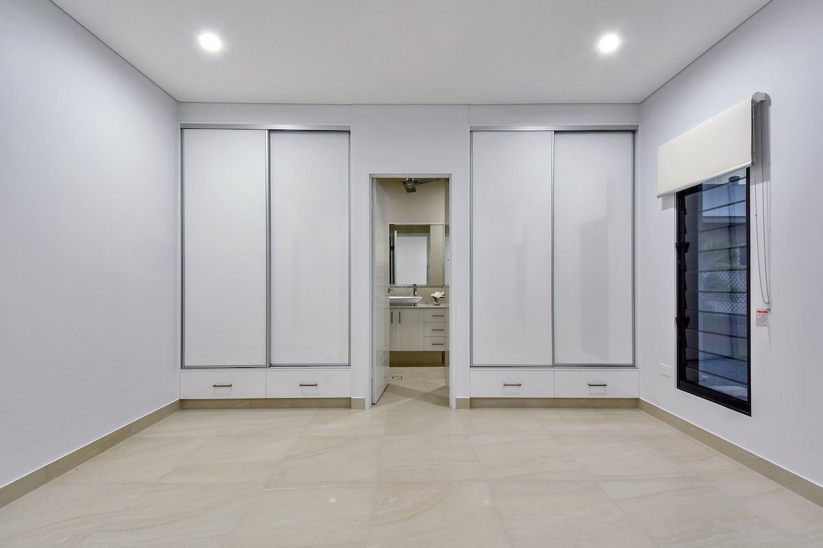 An empty room with white walls and sliding doors leading to a bathroom