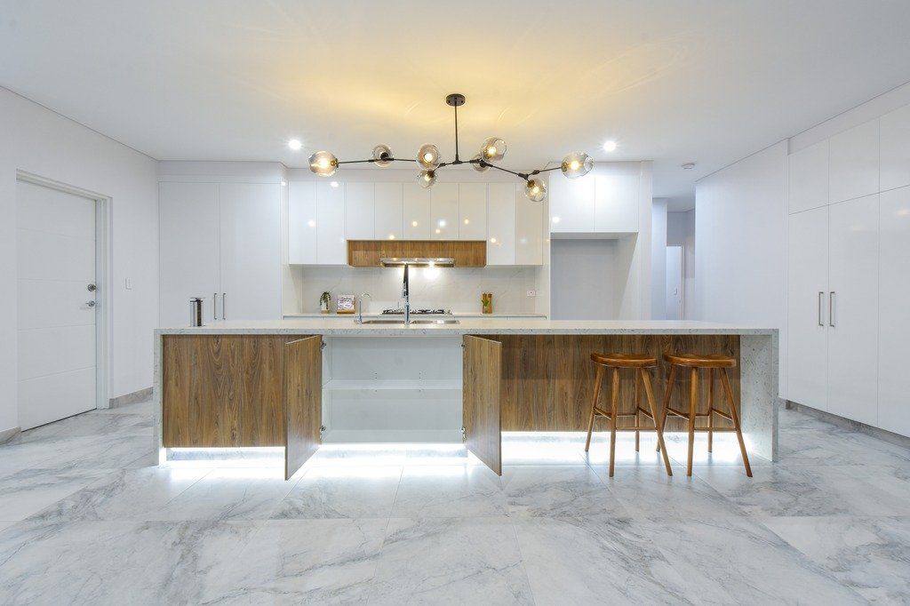 A modern kitchen with a large island and stools.