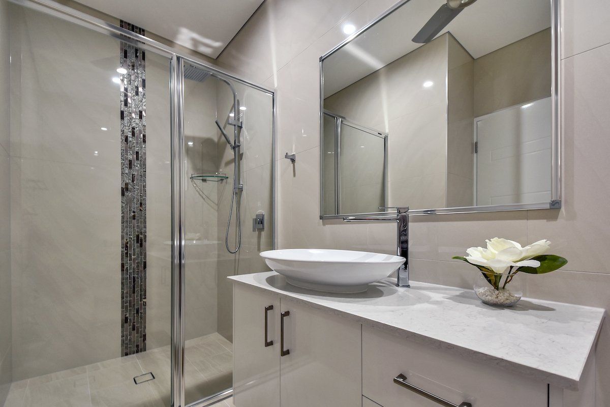 A bathroom with a sink , mirror and shower.